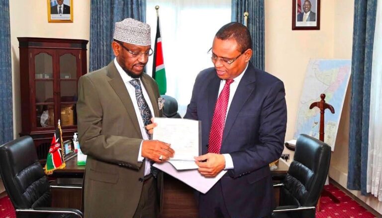 Somali Deputy Prime Minister Jibril Abdirashid Haji handed over his Kenyan passport on Monday to Kenya's Deputy Ambassador to Somalia, Elias Bare Shill (right). (Photo: Handout)